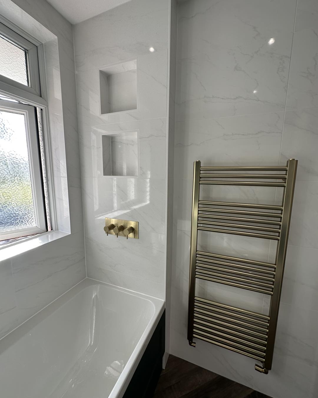 white marble tiled bathroom with gold hardware