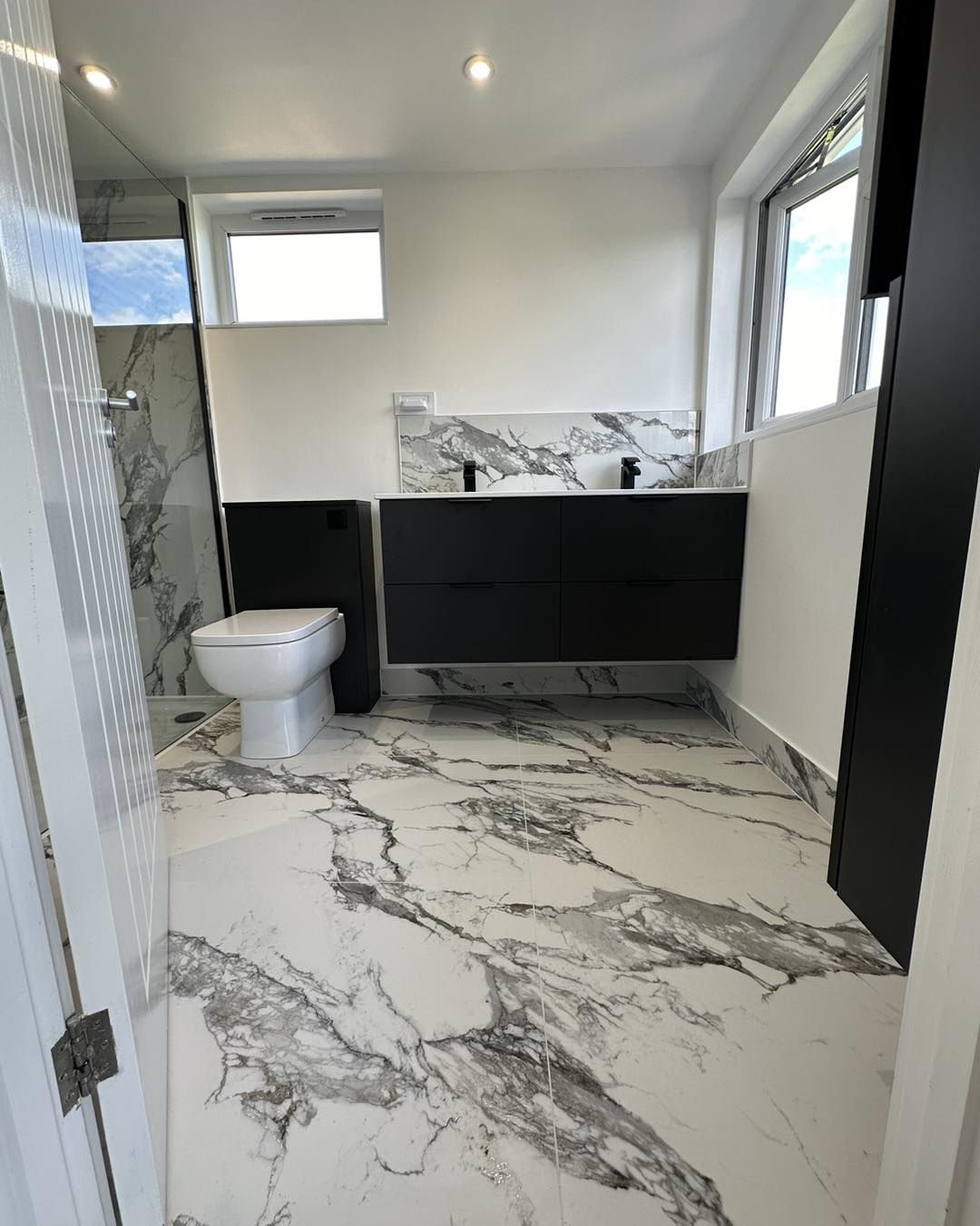 Black bathroom furniture against white marble tiles