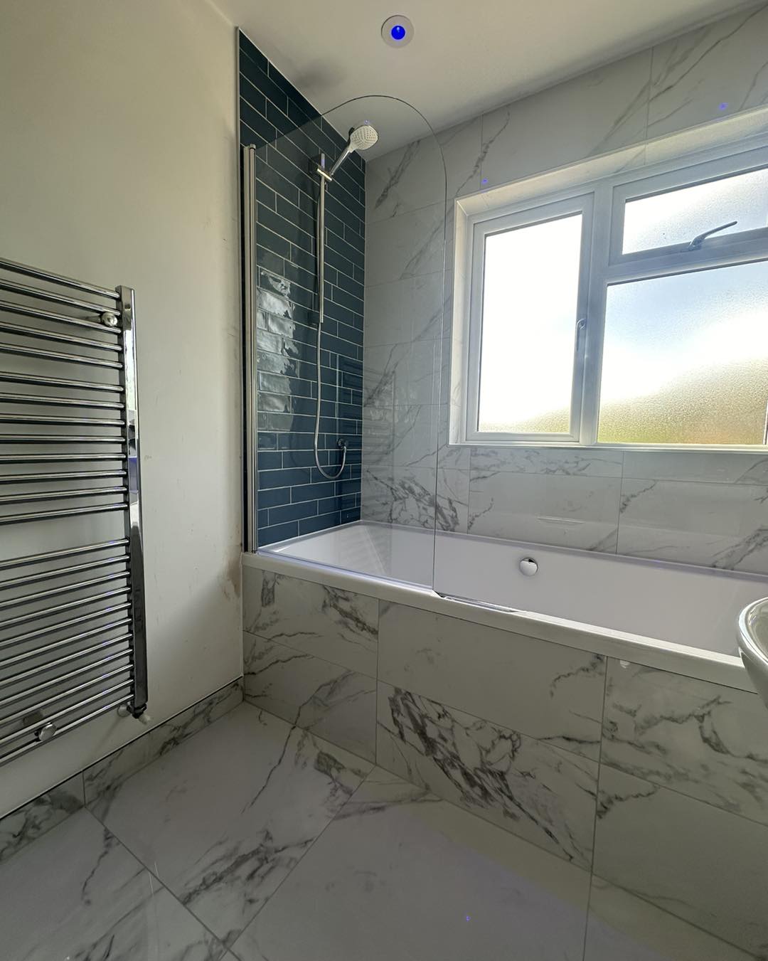 White marble tiled bathroom with navy shower area